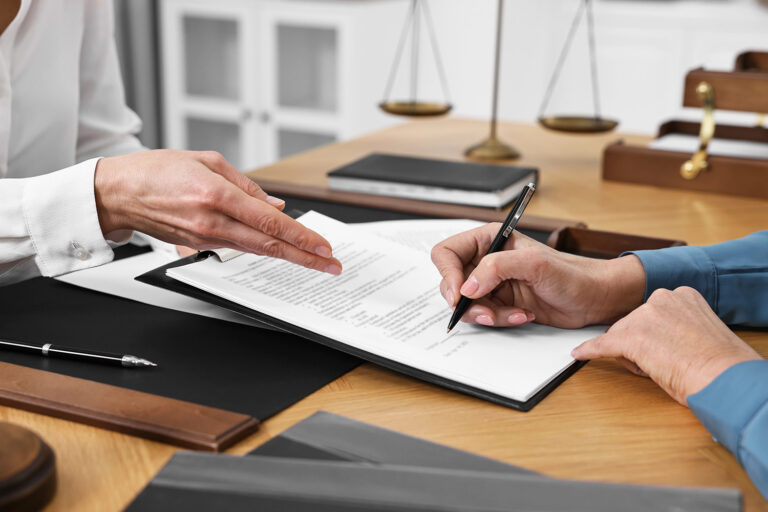 Senior woman signing document in lawyer's office, closeup